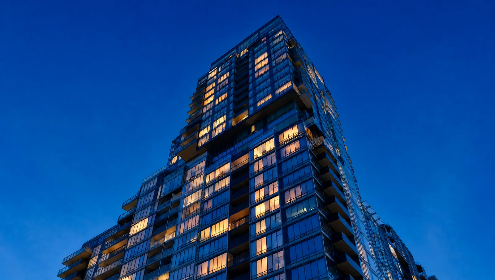 Illustrative image: a condominium tower at blue hour